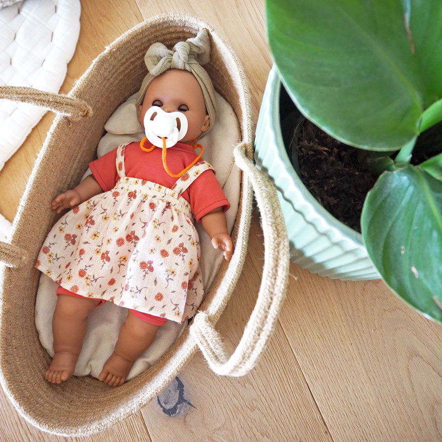 Puppe Maja liegt mit Schnuller im Babytragekorb und hat die Augen geschlossen