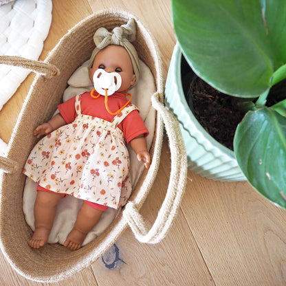 Puppe Maja liegt mit Schnuller im Babytragekorb und hat die Augen geschlossen